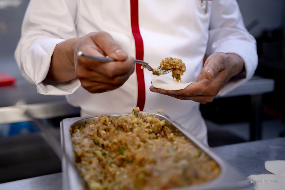 Spooning the spiced momo filling onto a wrapper